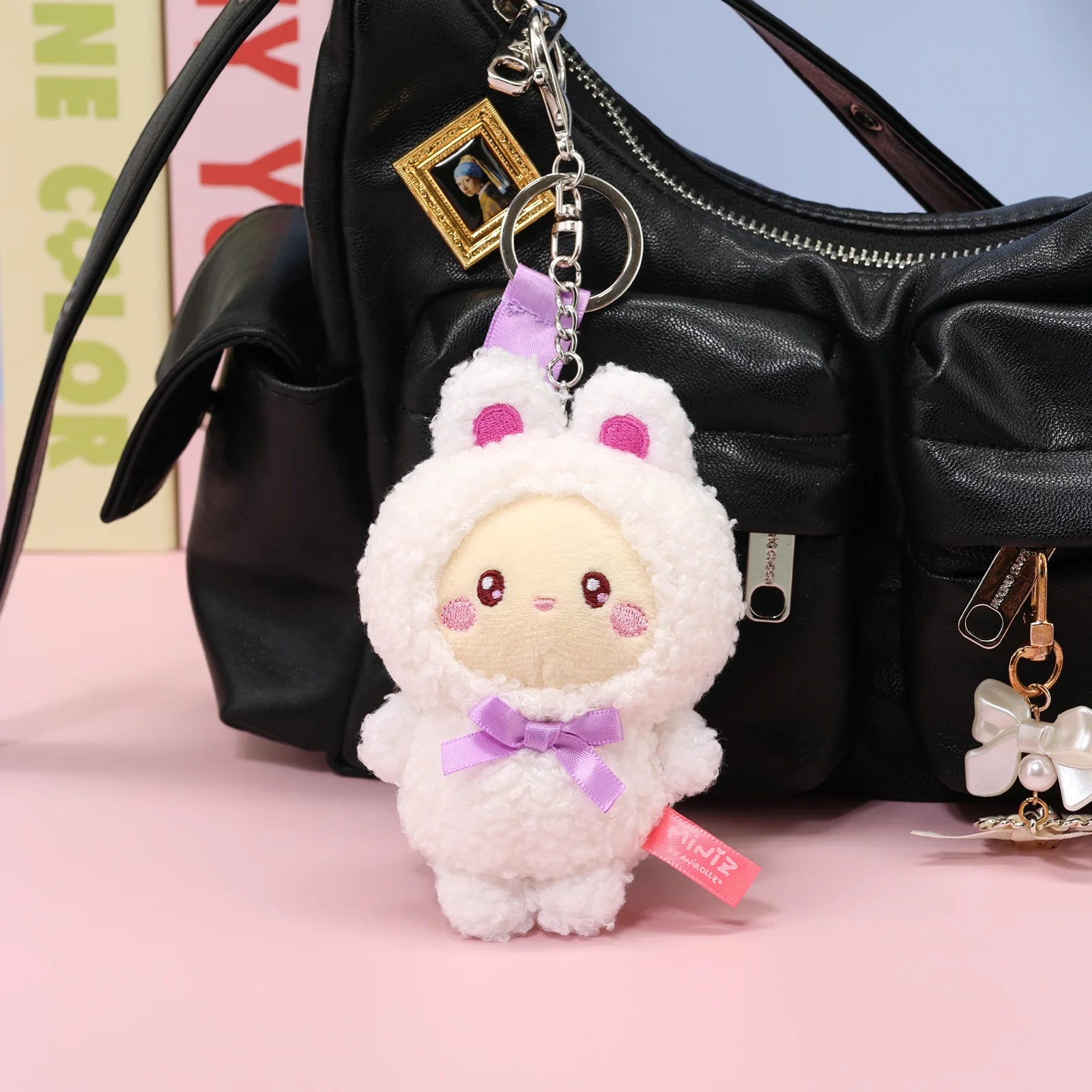 Front view Bunny Costume Bunniroll Plush Charm in front of black purse