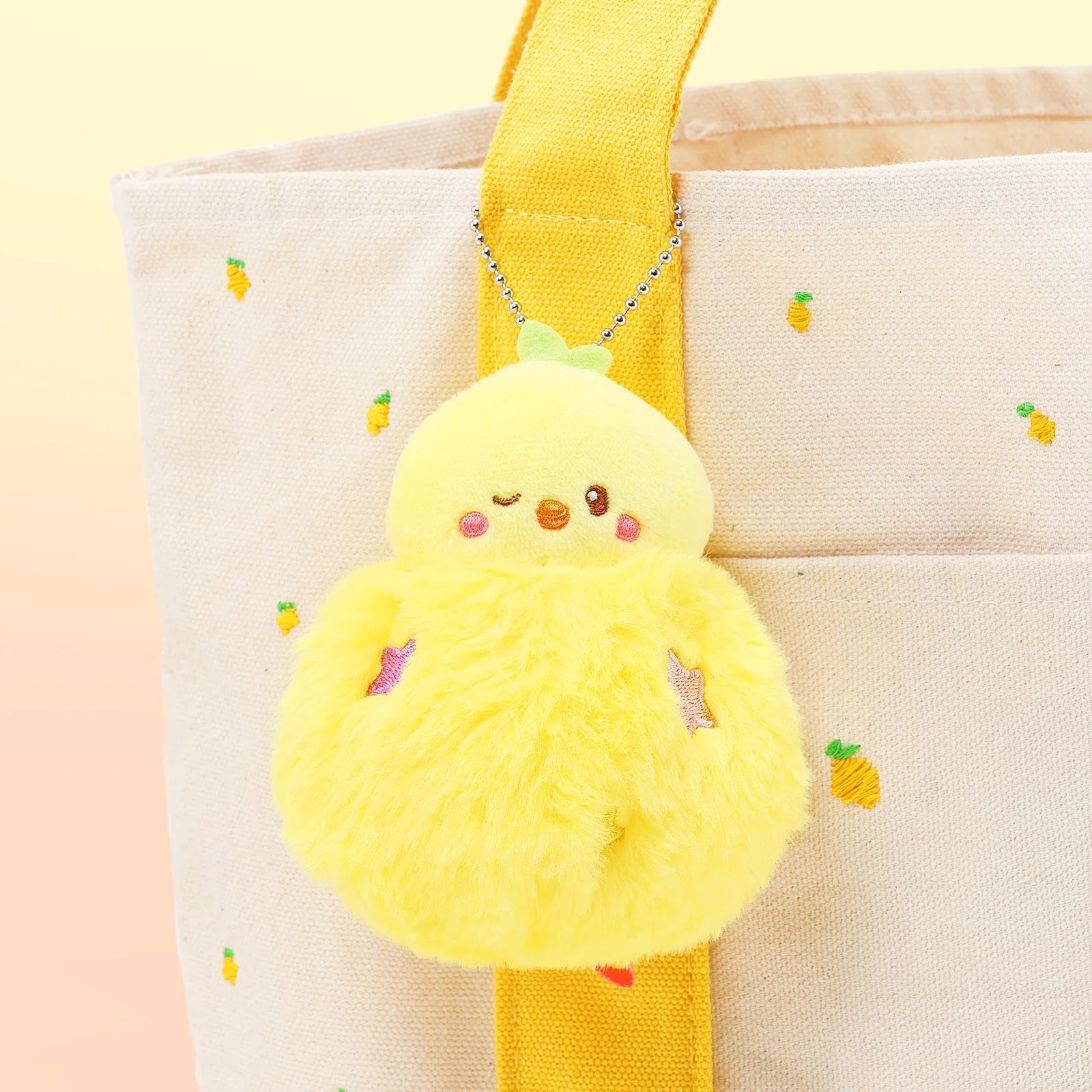 Front view Fluffy Ball Chickiroll Plush Charm in front of pink bag with embroidered lemons